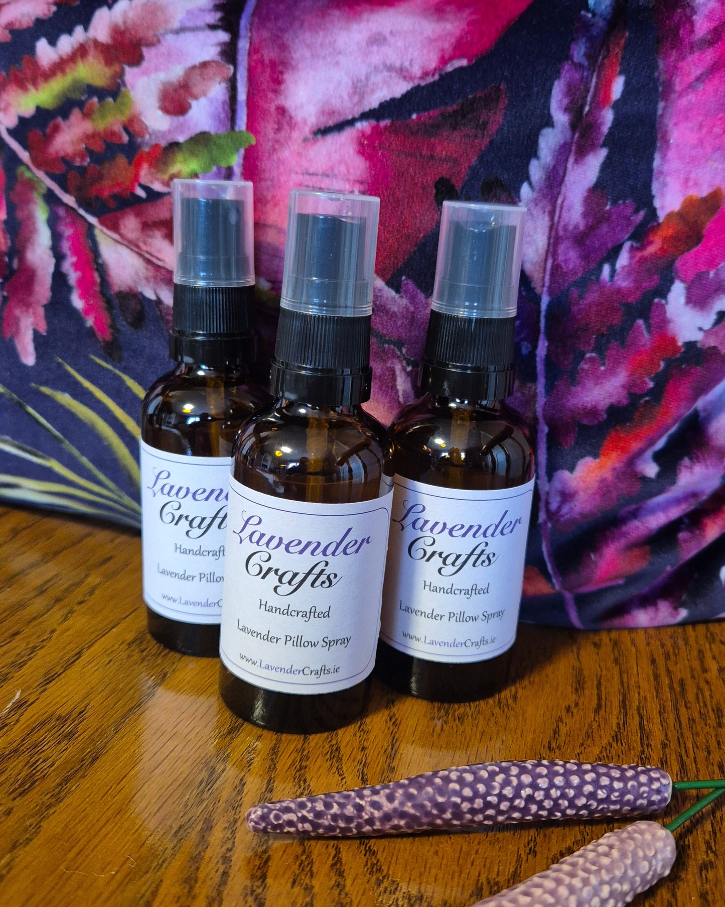 Three bottles of Lavender Gold essential oils on a colorful fabric background